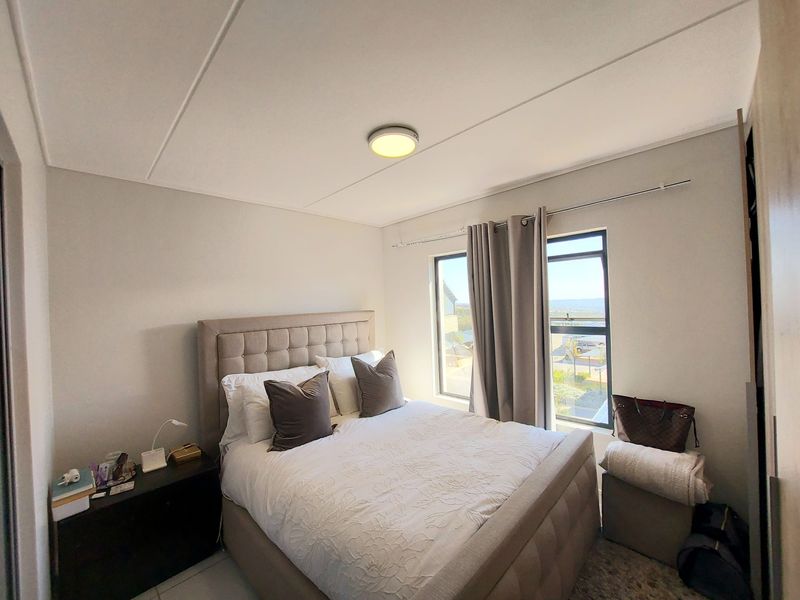 A well-lit bedroom featuring tiled flooring, a built-in cupboard, and a window with natural light.