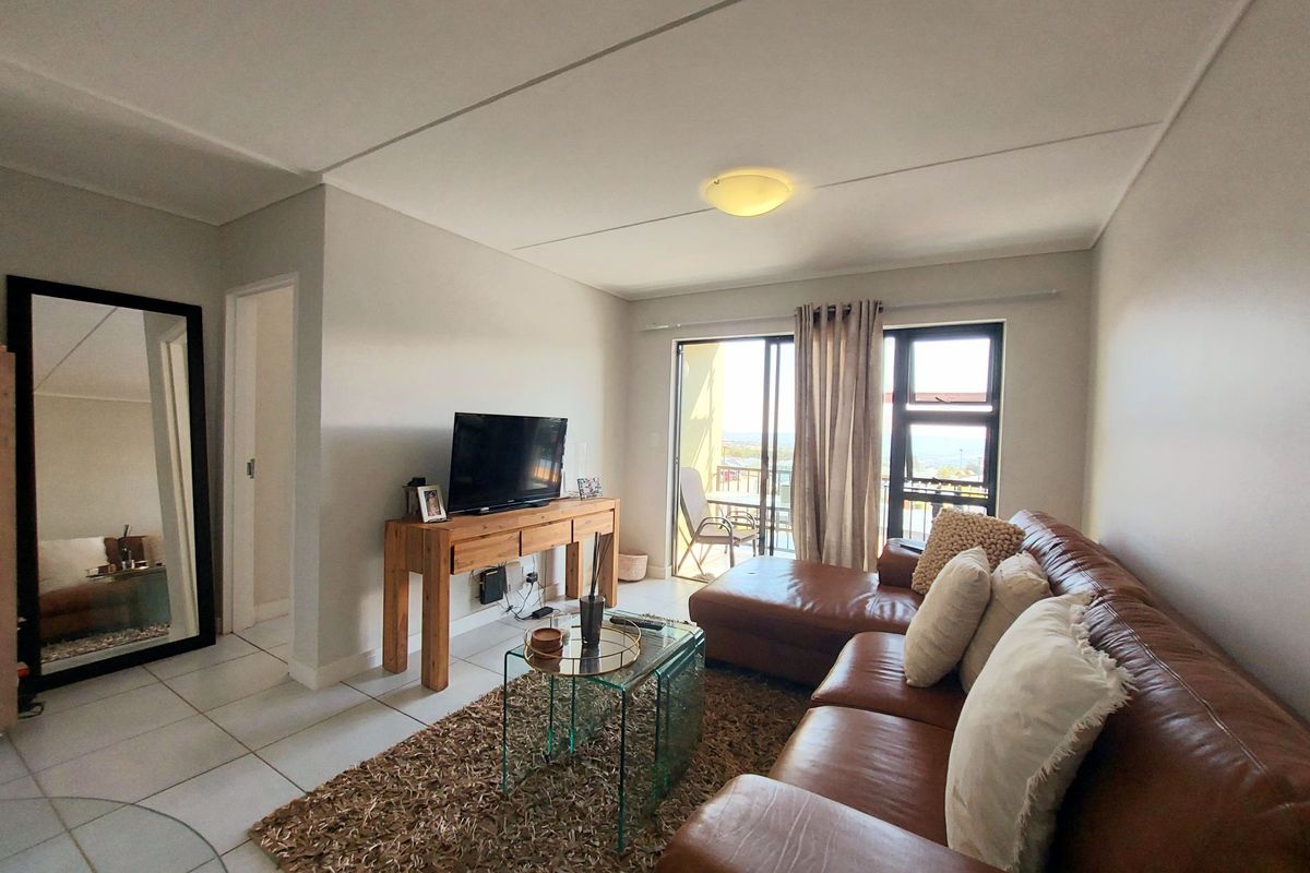 A bright living room featuring tiled flooring and a sliding glass door that provides access to an outdoor balcony area.