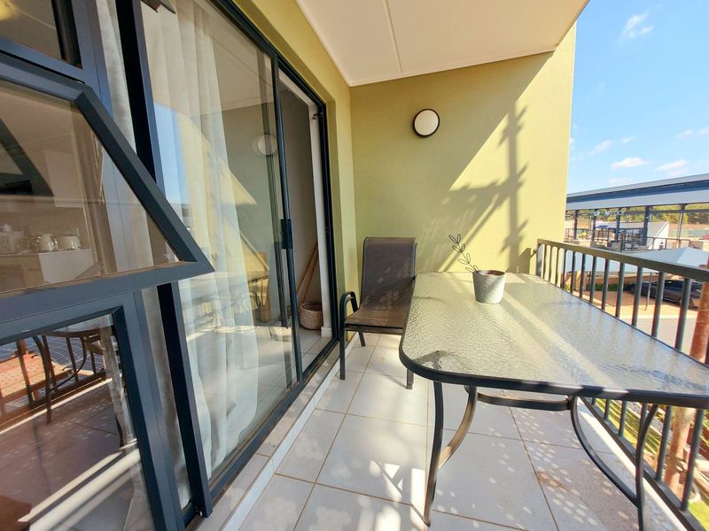 A covered balcony featuring tiled flooring, a metal balustrade, and large sliding glass doors providing access to the interior living space.