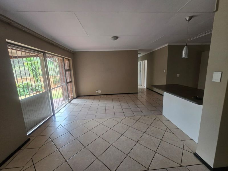 Spacious open-plan living area featuring tiled flooring, a breakfast counter, and large sliding glass doors providing access to the exterior.