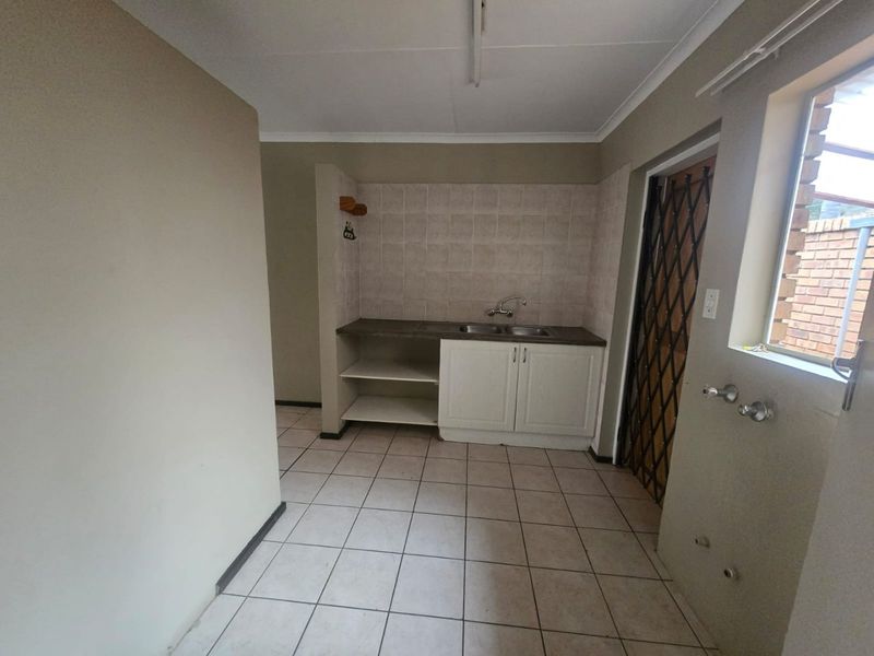 A functional laundry area featuring a double sink, built-in cabinetry, tiled splashback, and dedicated plumbing connections for appliances.