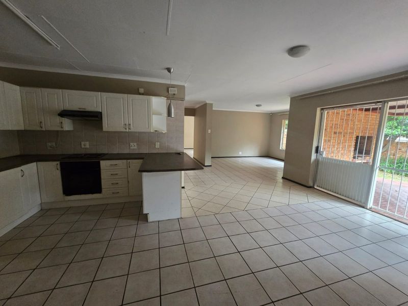 Spacious open-plan kitchen and living area featuring tiled flooring, built-in cabinetry, and direct access to the outdoor patio through a sliding glass door.