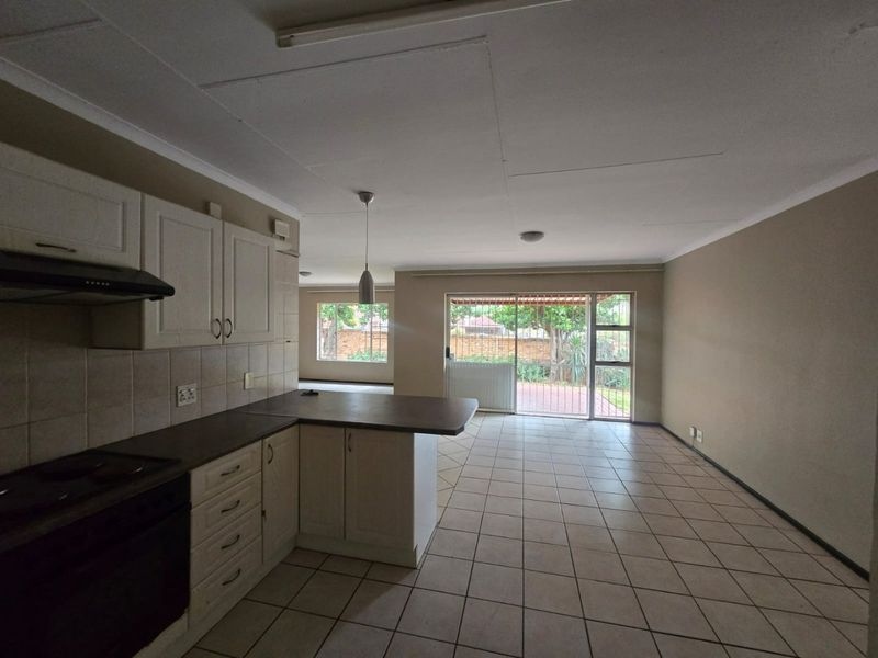 Spacious open-plan kitchen and living area featuring tiled flooring, built-in cabinetry, and direct access to the rear garden through a sliding glass door.