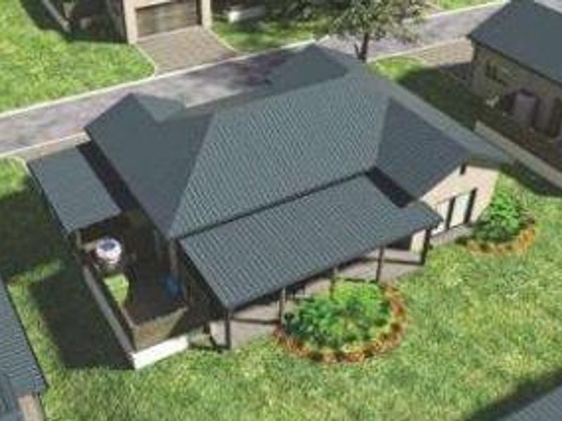 An aerial view of a townhouse featuring a metal roof, a covered patio area, and surrounding landscaped garden space.