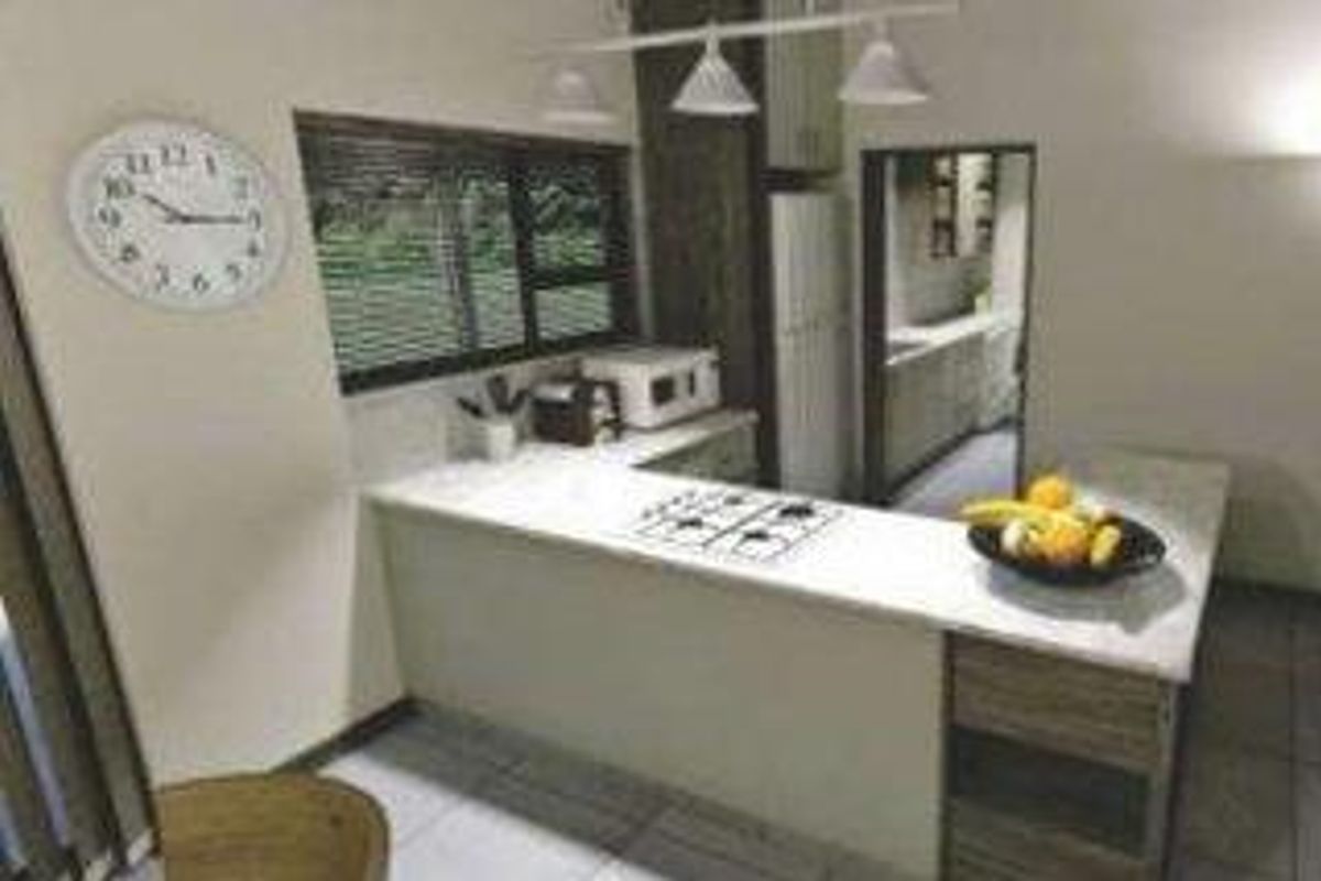 A functional kitchen featuring a breakfast bar, gas hob, stone countertops, and built-in cabinetry, with an adjacent scullery area visible.