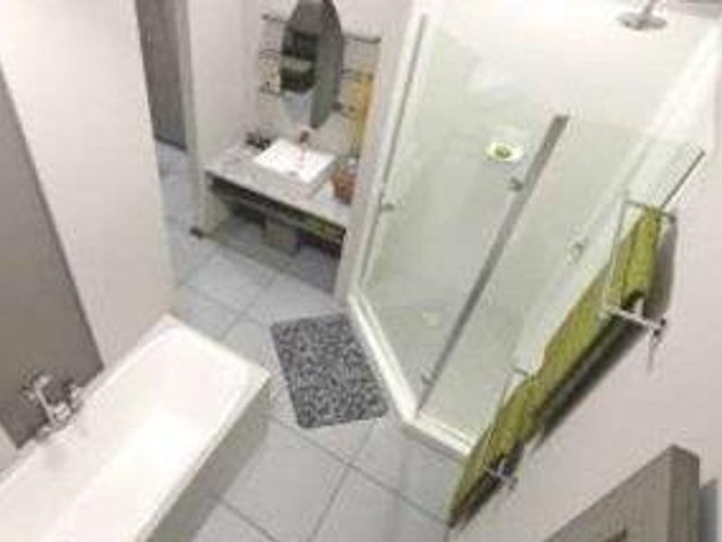 Modern bathroom featuring a built-in bathtub, separate shower enclosure, and a vanity basin with wall-mounted mirror.