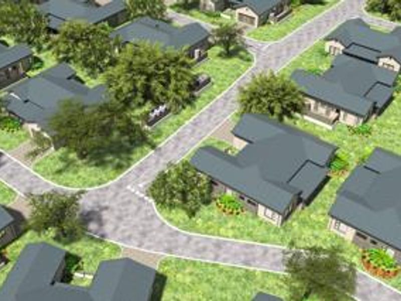 An aerial view of a residential townhouse complex featuring multiple units with pitched roofs, paved access roads, and established garden areas.