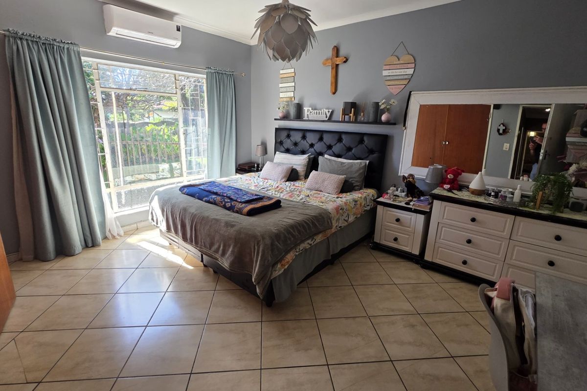 Spacious bedroom featuring tiled flooring, a split-system air conditioner, and a large window providing natural light.