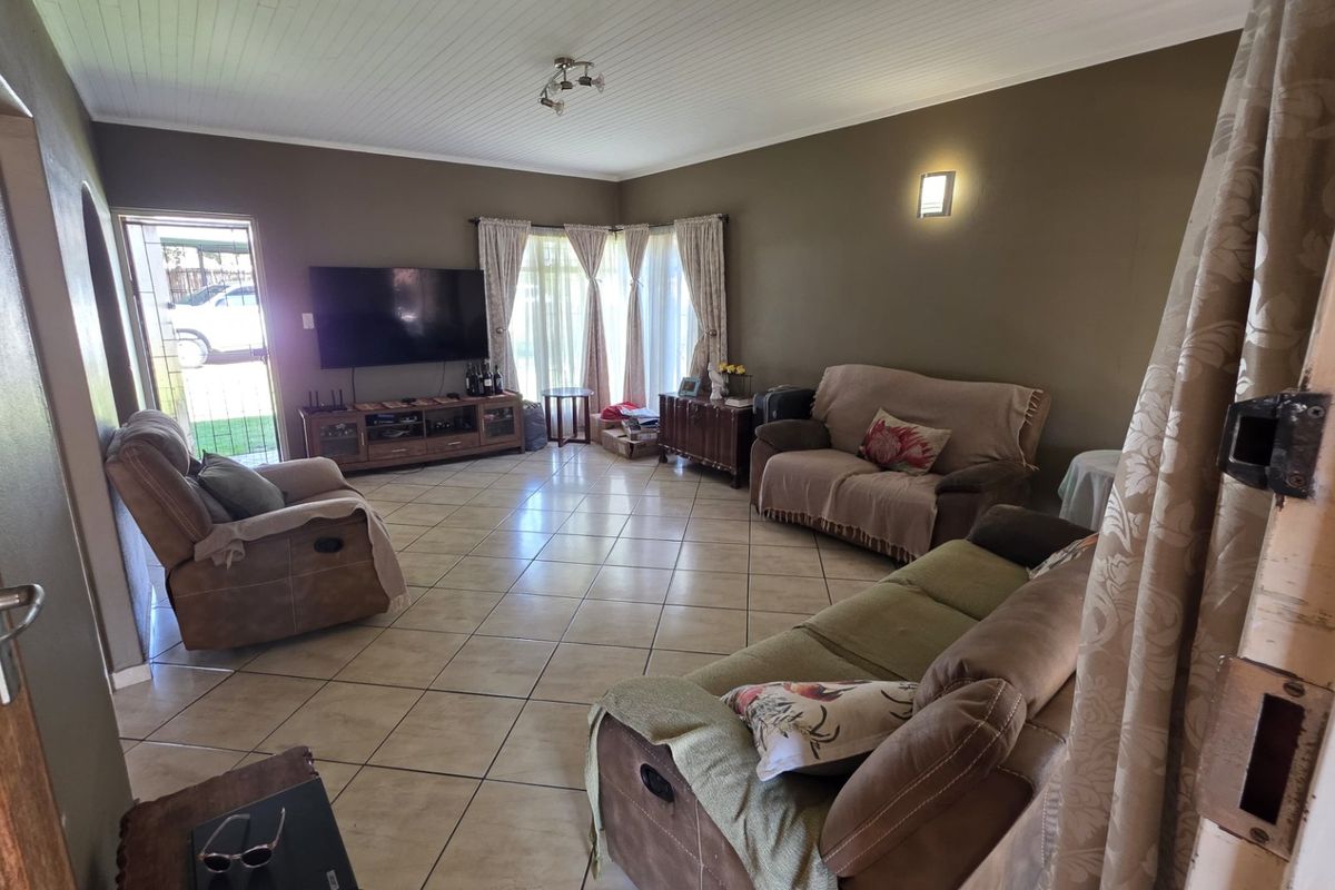 Spacious living room featuring tiled flooring, a tongue and groove ceiling, and a sliding glass door providing access to the exterior.