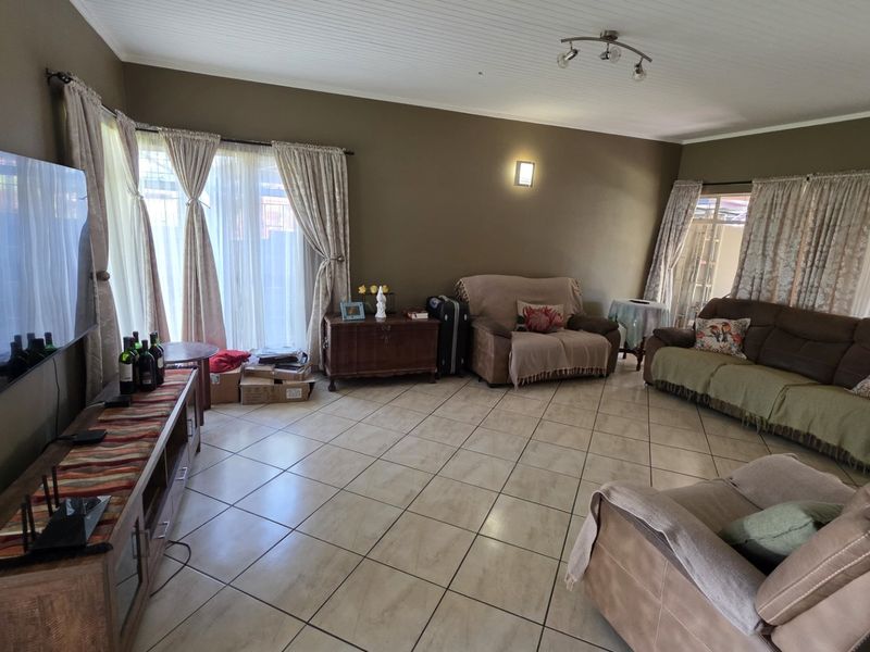 Spacious living room featuring tiled flooring, beadboard ceiling, and large sliding glass doors providing natural light and access to the exterior.