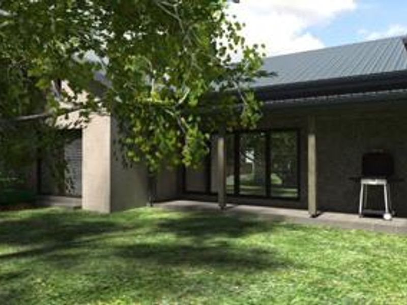 A covered outdoor patio area featuring a metal roof, timber support posts, and large sliding glass doors leading into the home.