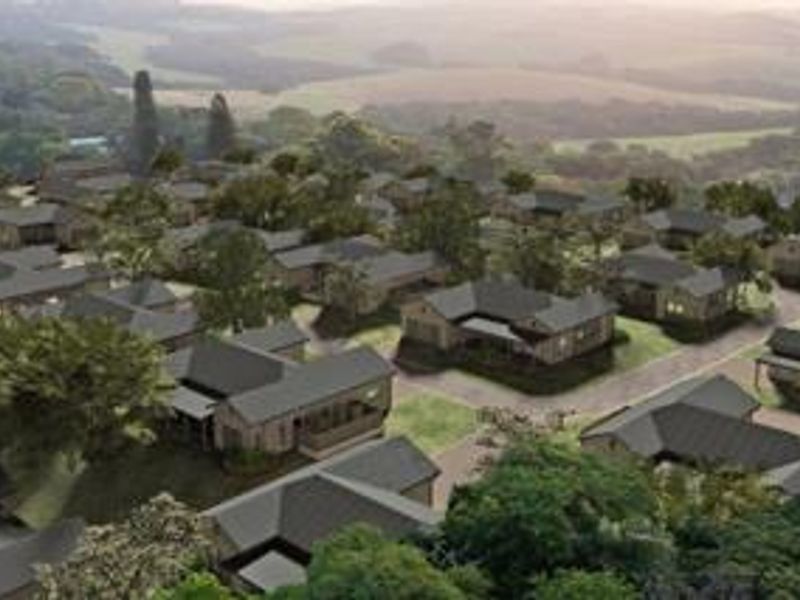 An aerial view of a residential townhouse estate featuring multiple units with pitched roofs set within a landscaped environment.
