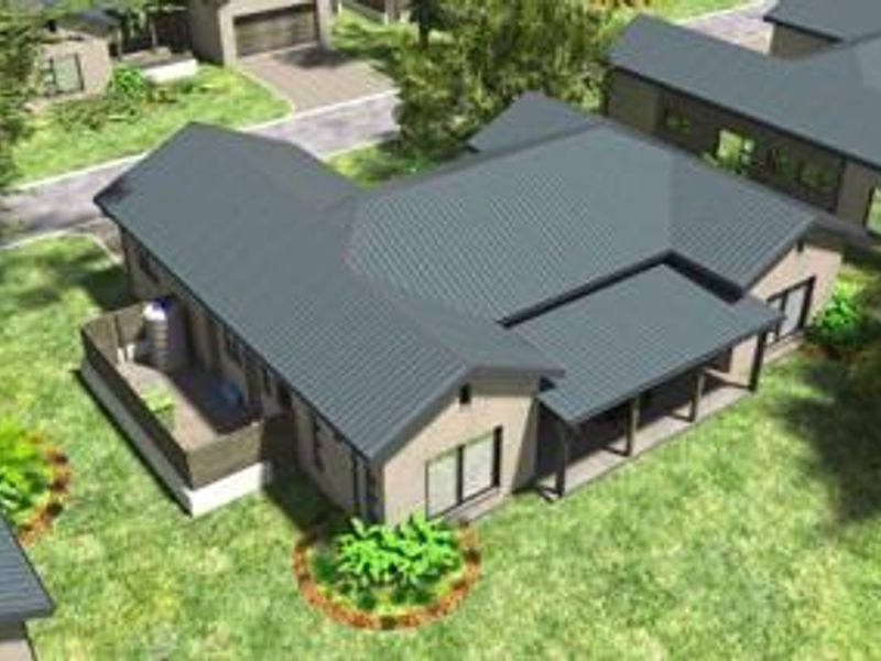 Aerial view of a modern townhouse featuring a metal roof, covered patio, and landscaped garden area within a residential estate.