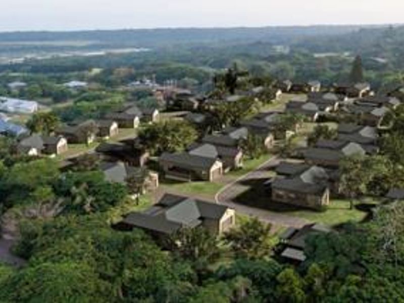 An aerial view of a residential townhouse development set within a lush, green landscape, showcasing the layout and surrounding environment.
