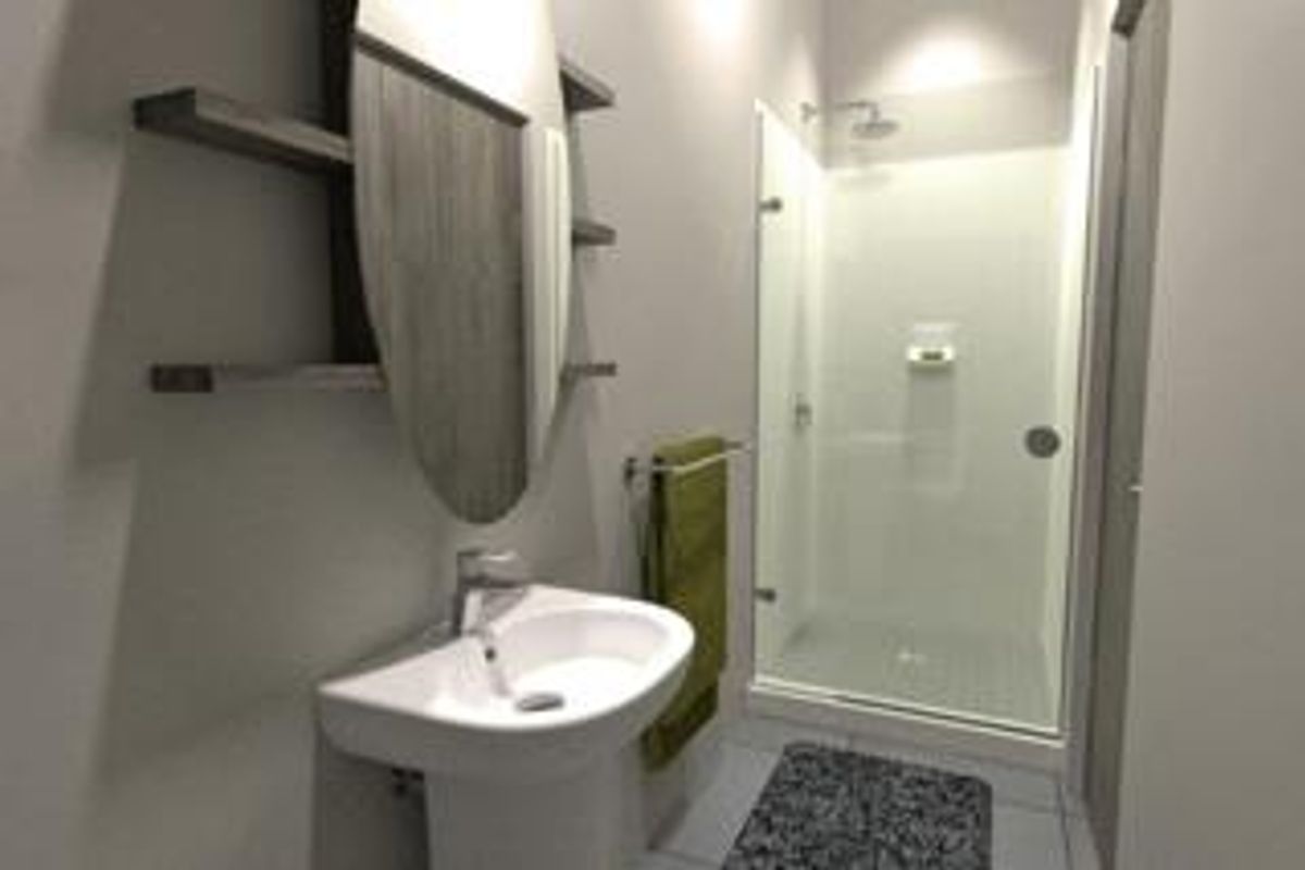 Modern bathroom featuring a pedestal basin, glass-enclosed shower, and built-in shelving with neutral wall finishes and tiled flooring.