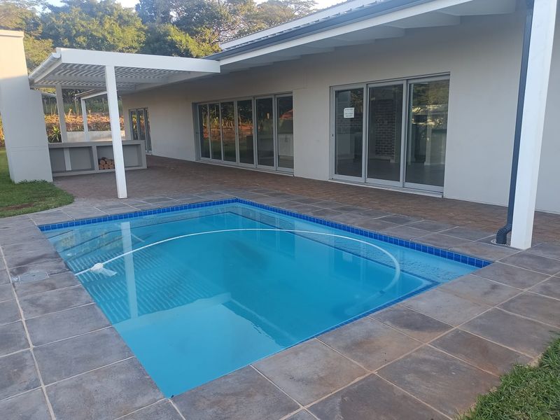 Outdoor entertainment area featuring a swimming pool with tiled surround, covered patio space, and large sliding glass doors leading into the home.