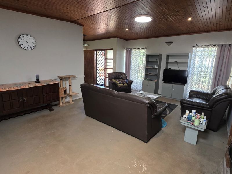 Spacious living room featuring a timber ceiling, stone feature wall, and built-in shelving units, offering a rustic foundation for modern updates.