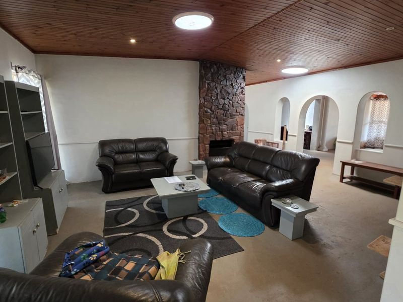 Spacious living room featuring a prominent stone fireplace, timber-clad ceiling, and architectural archways leading to adjacent areas.