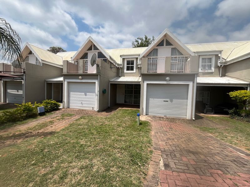 Front elevation of a townhouse complex featuring multiple garage doors, paved driveways, and upper-level balconies with gabled roof architecture.