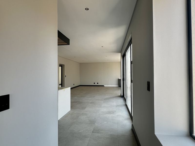 Spacious open-plan living area featuring large format floor tiles, recessed lighting, and sliding glass doors leading to an outdoor space.