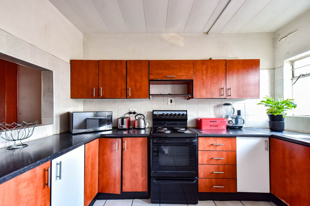 A functional kitchen featuring wood-tone cabinetry, dark countertops, and a built-in electric stove with an extractor fan.