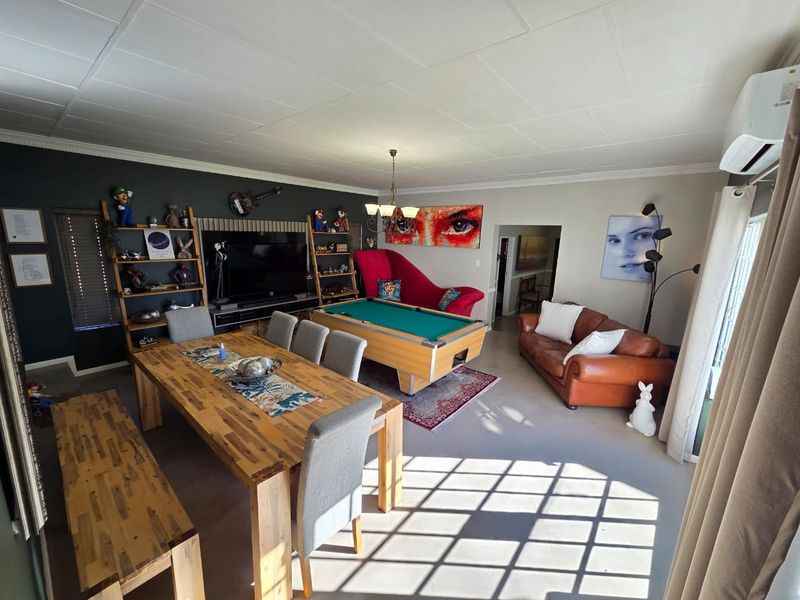 Spacious open-plan living and dining area featuring a tiled ceiling, split-system air conditioning, and large windows allowing for ample natural light.