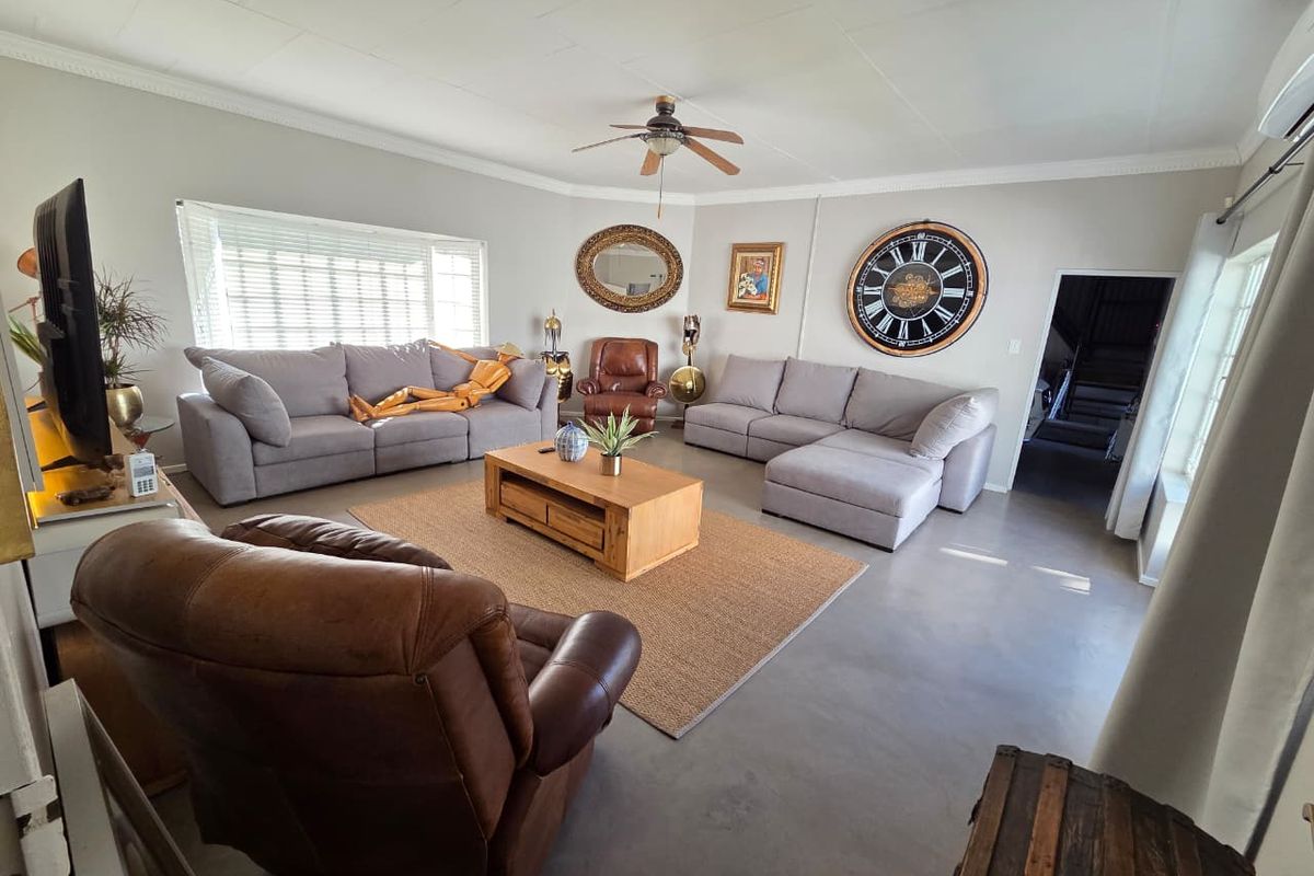 Spacious living room featuring neutral walls, polished concrete flooring, a ceiling fan, and an integrated air conditioning unit.