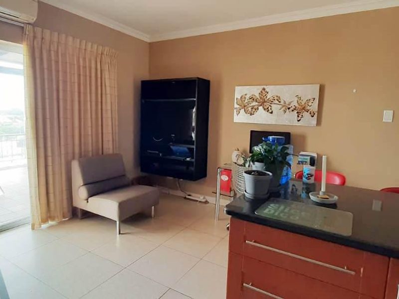 Open-plan living area featuring tiled floors, a kitchen with granite countertops, and a sliding door providing access to an outdoor balcony.