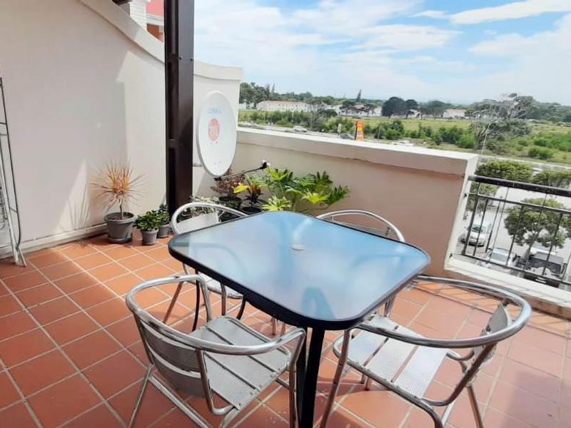 A covered balcony featuring tiled flooring and metal railings, offering an elevated view of the surrounding area.