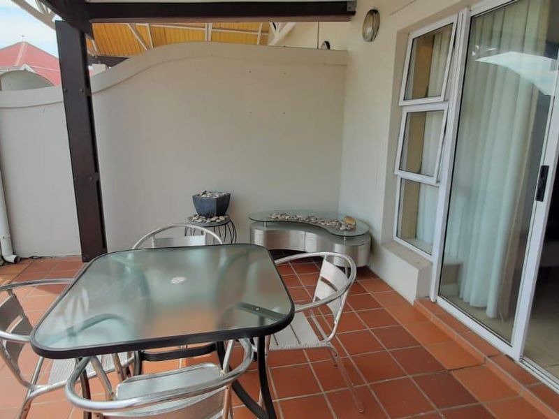 A covered balcony featuring tiled flooring, a metal balustrade, and direct access to the interior through a sliding glass door.