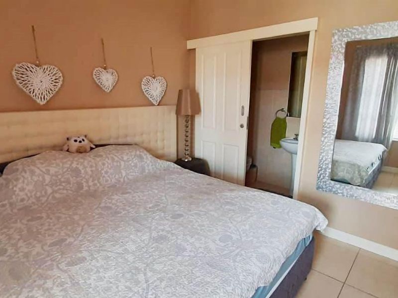 A bedroom featuring tiled flooring and a sliding door providing access to an en-suite bathroom.