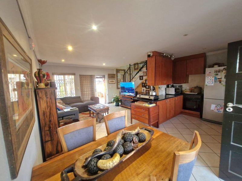 Open-plan living and dining area featuring a functional kitchen with built-in cabinetry, oven, and hob, seamlessly connected to the main living space.