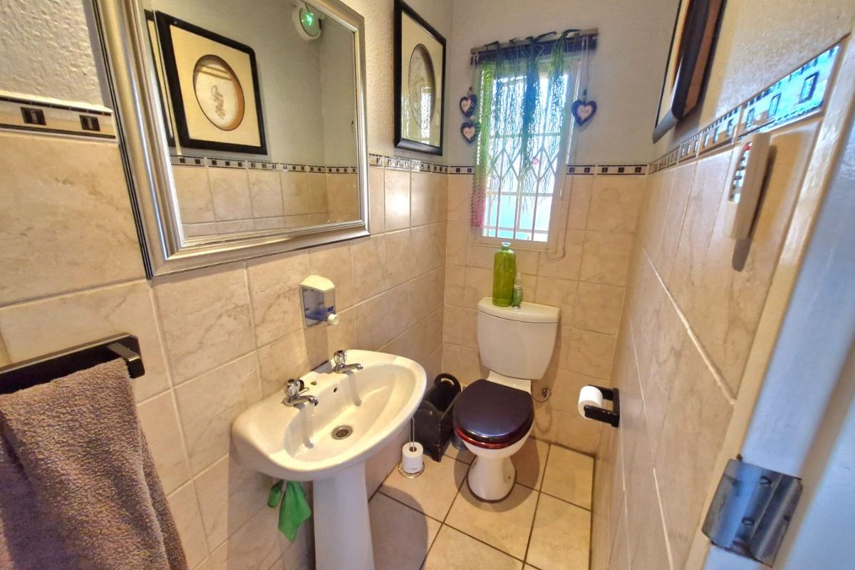 A compact guest bathroom featuring a pedestal basin, toilet, and neutral ceramic tiling throughout.