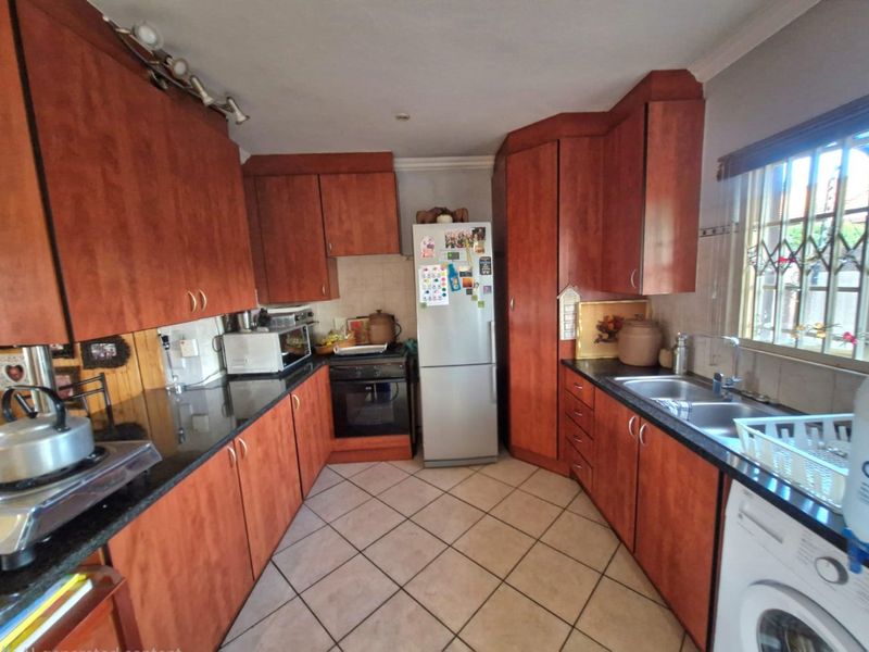 A functional kitchen featuring wood-finish cabinetry, granite countertops, tiled flooring, and integrated appliances, offering a practical layout for daily meal preparation.