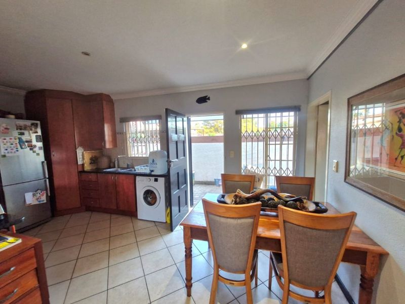 Open-plan kitchen and dining area featuring tiled flooring, built-in cabinetry, and direct access to an outdoor patio area through security gates.