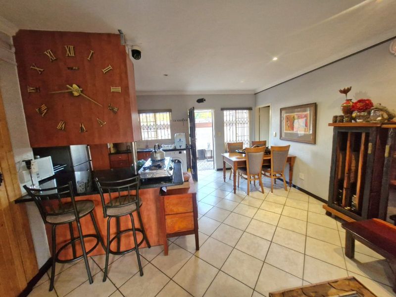 Open-plan living and dining area featuring tiled flooring, a breakfast counter, and direct access to the exterior through a security gate.