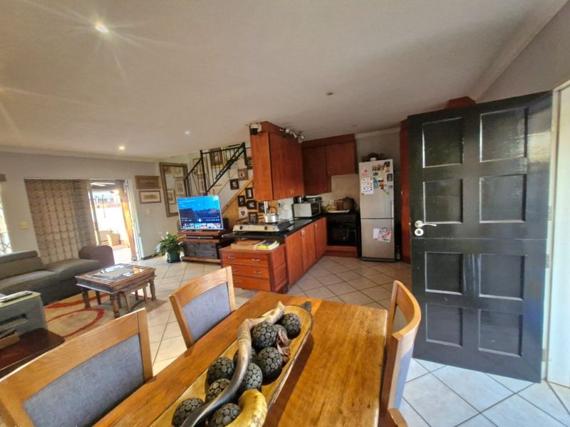 Open-plan living and kitchen area featuring wooden cabinetry, granite countertops, tiled flooring, and a staircase leading to the upper level.