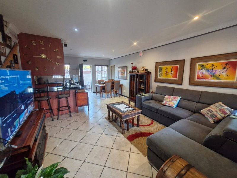 Spacious open-plan living and dining area featuring a kitchen island with granite countertops, tiled flooring, and recessed lighting throughout the main living space.