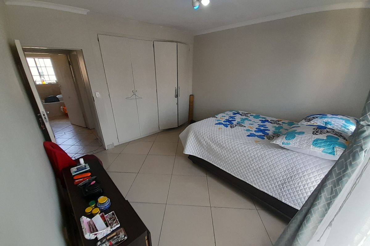 A bedroom featuring tiled flooring, built-in cupboards, and direct access to an adjoining bathroom.