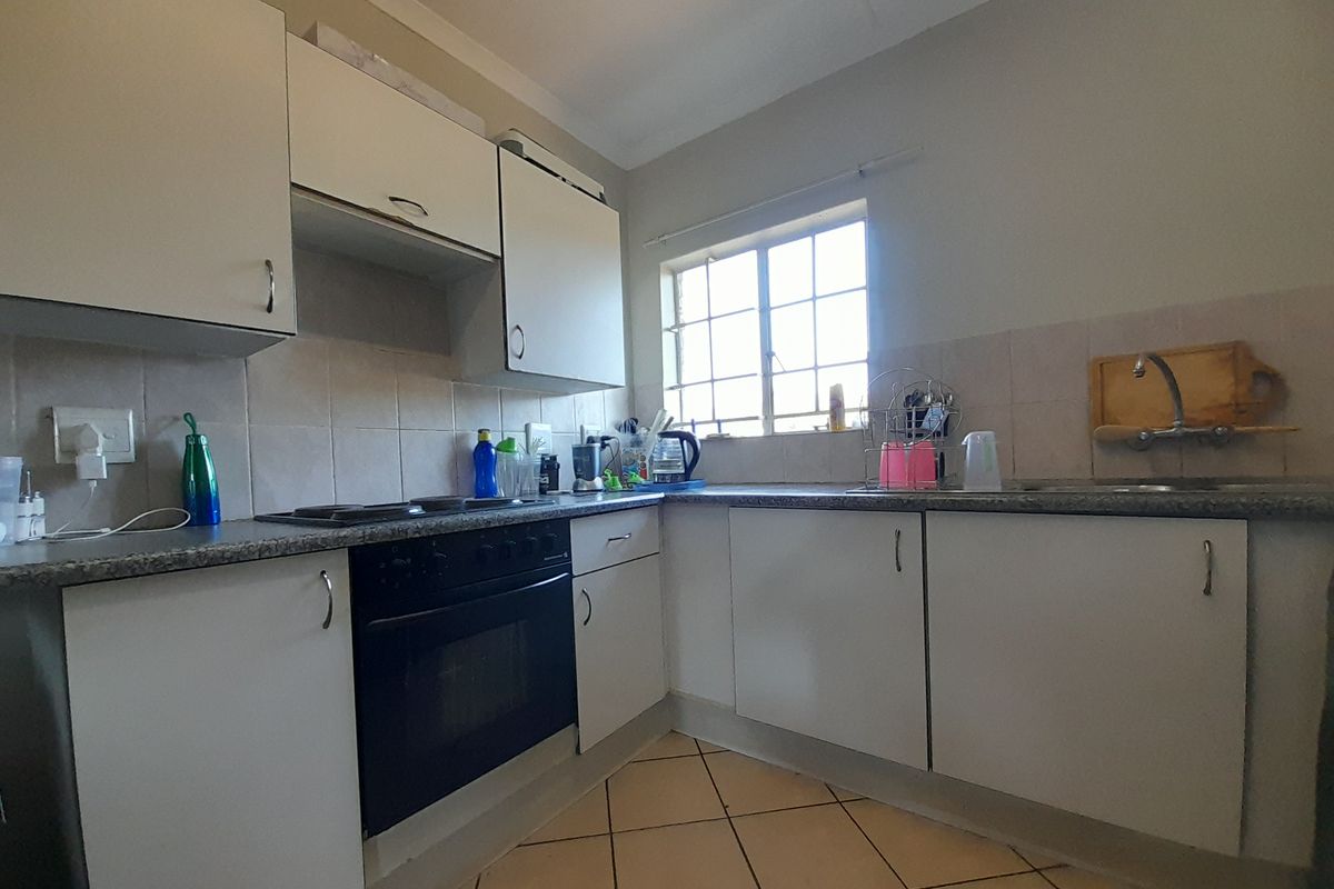 A functional kitchen featuring built-in cabinetry, a tiled backsplash, an integrated oven and hob, and tiled flooring.