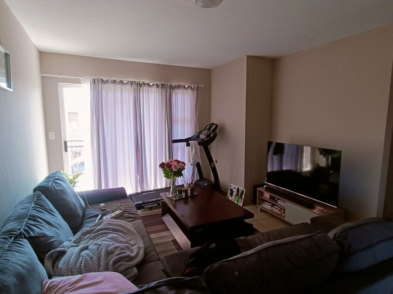 A comfortable living room featuring tiled flooring and a sliding glass door that provides access to an outdoor balcony area.