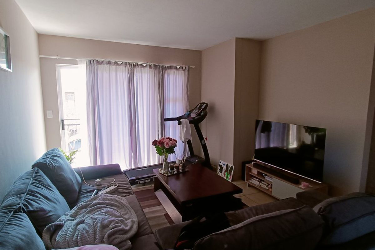 A comfortable living room featuring tiled flooring and a sliding glass door that provides access to an outdoor balcony area.