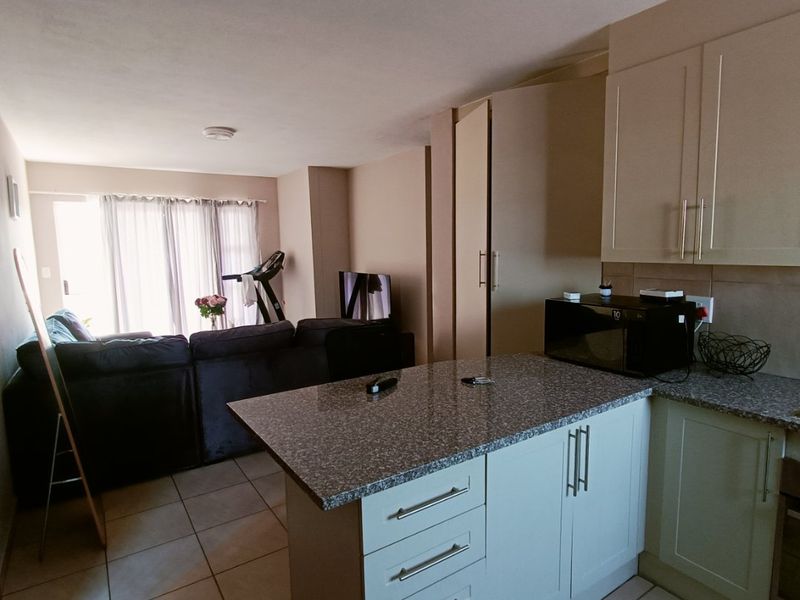 Open plan kitchen and living area featuring granite countertops, modern cabinetry, tiled flooring, and direct access to a patio through sliding glass doors.