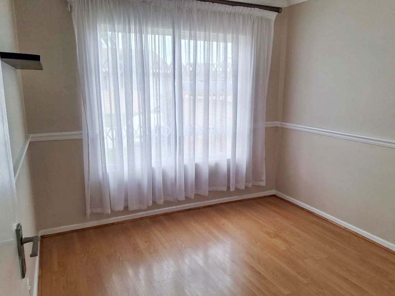 An empty bedroom featuring laminate flooring and classic chair rail molding, providing a neutral canvas for personalization.