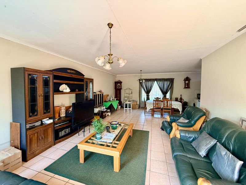 Spacious open-plan living and dining area featuring tiled flooring and neutral walls, offering a versatile layout for family living and entertaining.