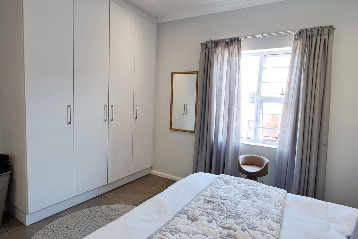 A well-maintained bedroom featuring neutral walls, tiled flooring, and ample built-in cupboard storage space.
