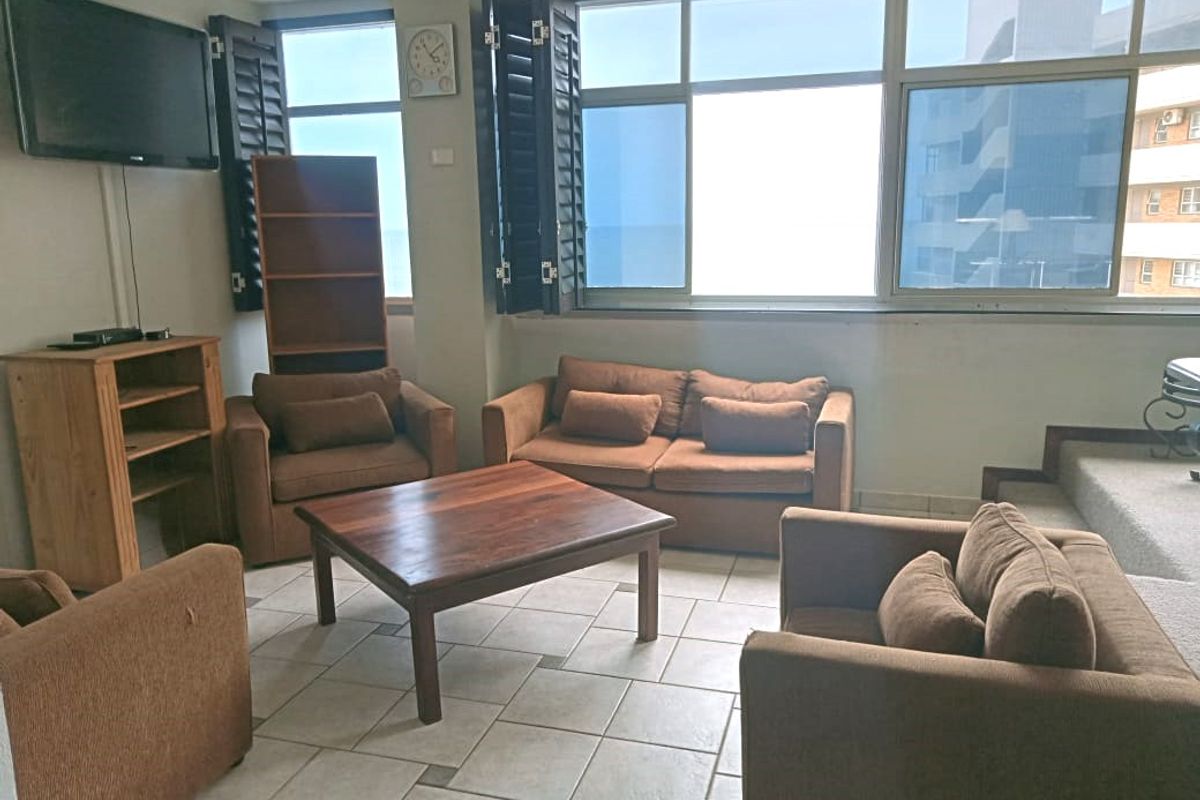 A living room featuring large windows with shutters, tiled flooring, and a raised platform area.