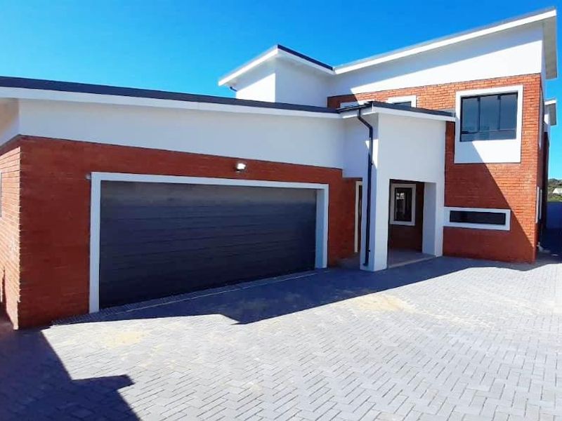 Modern double-storey residential home featuring a contemporary brick and render facade with a spacious paved driveway and integrated double garage.