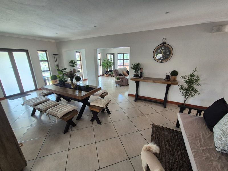 Spacious open-plan living and dining area featuring neutral tiled flooring, recessed lighting, and large glass doors providing ample natural light.