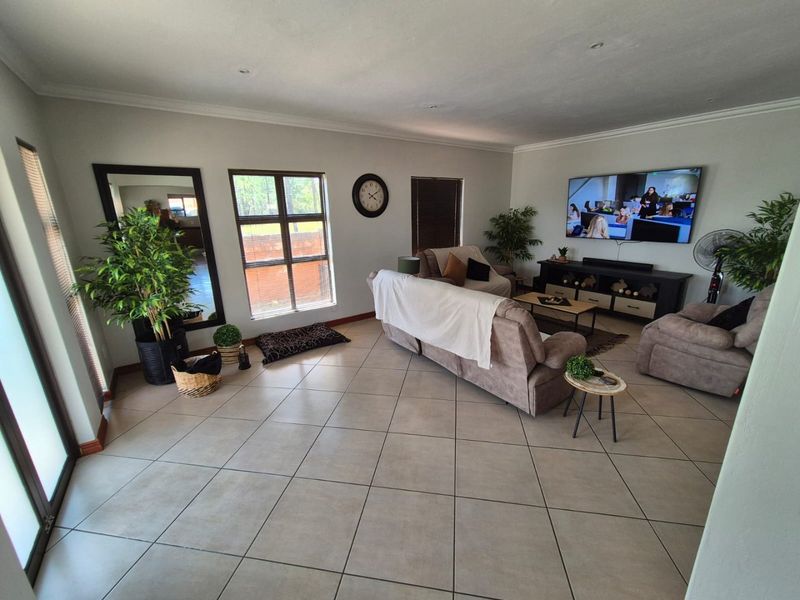 Spacious living room featuring neutral tiled flooring, recessed downlighting, and large windows providing ample natural light.